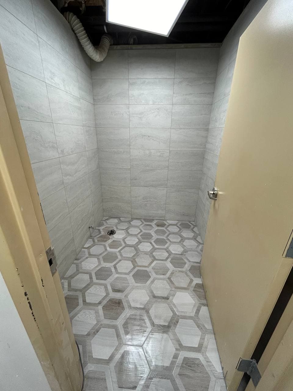 Gray tiled walk-in shower with mosaic floor, recessed niche, bench, and skylight