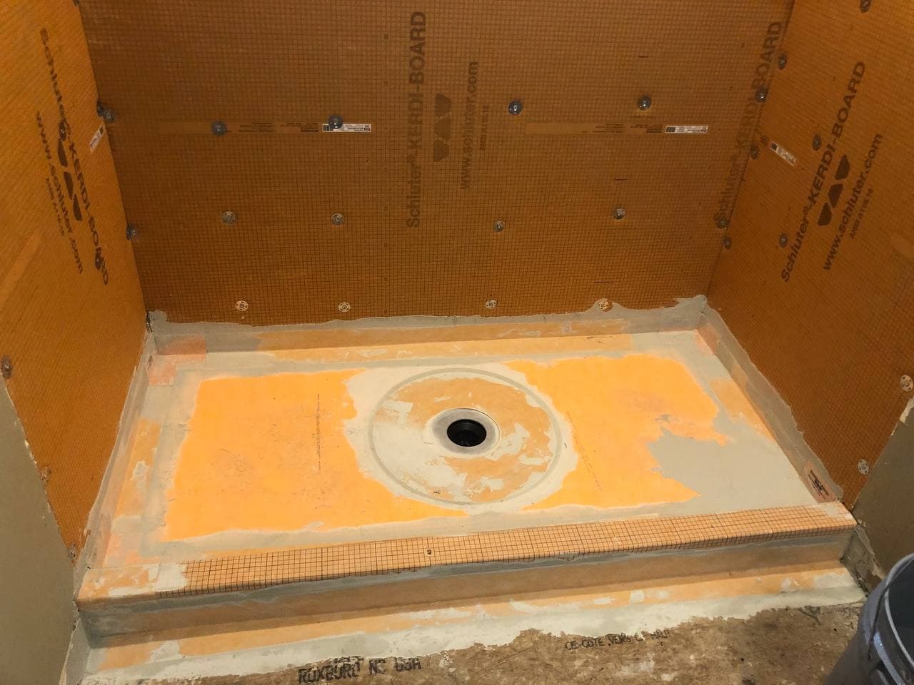 Shower base and walls prepared with an orange waterproofing system before tile