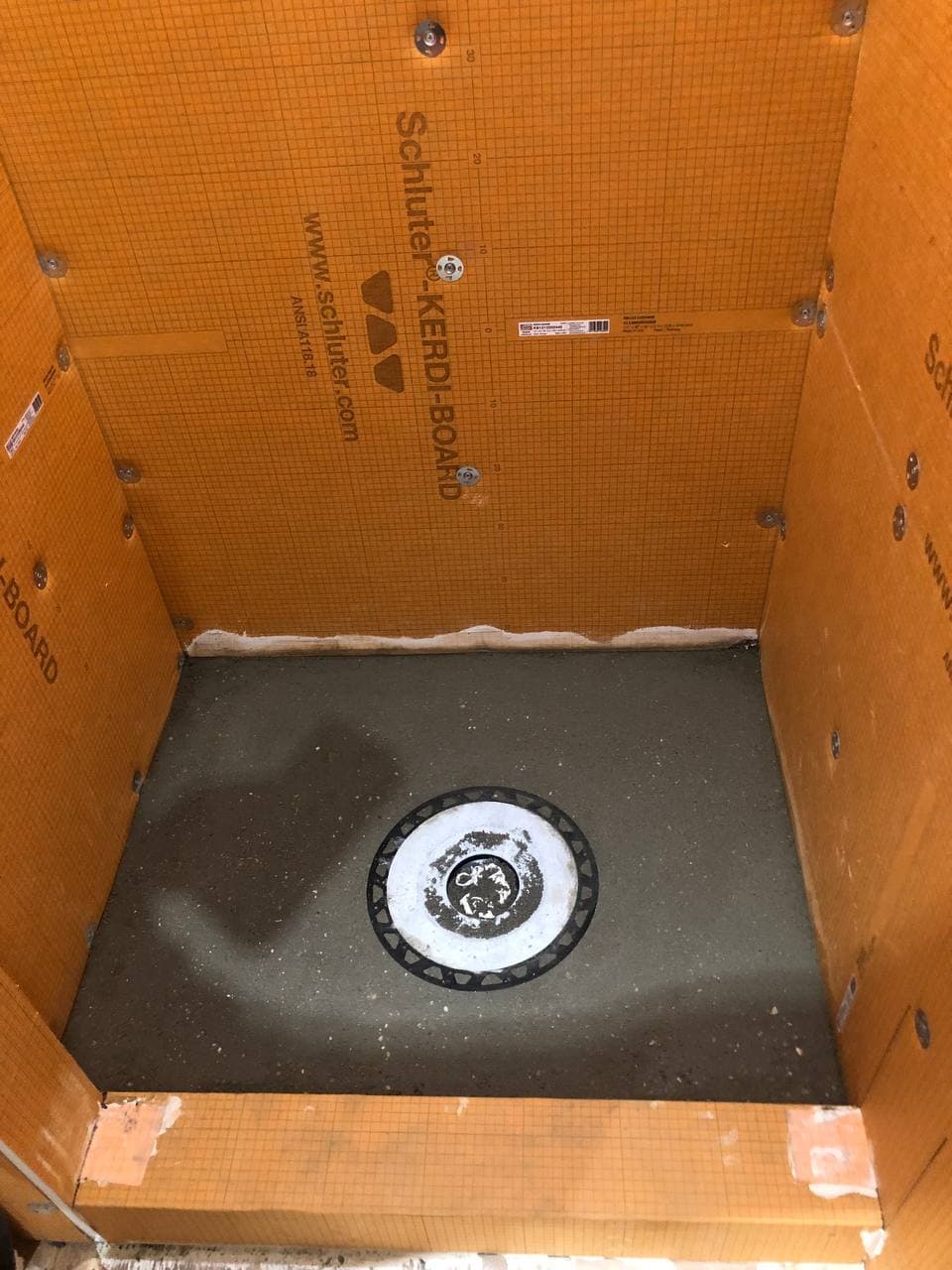 Close view of a square shower drain integrated into a waterproof shower base