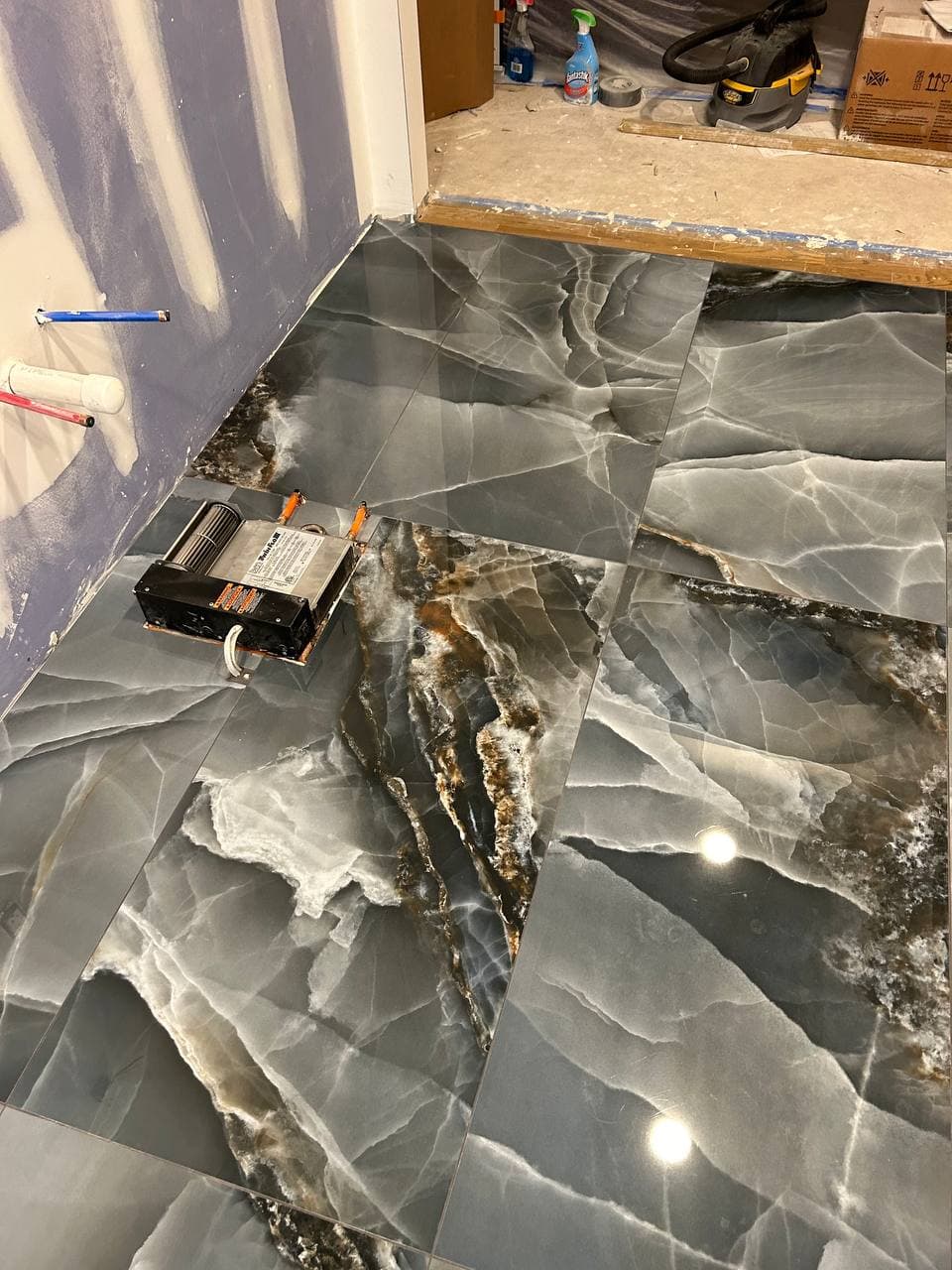 Polished black marble-look floor tile shown during installation and layout work