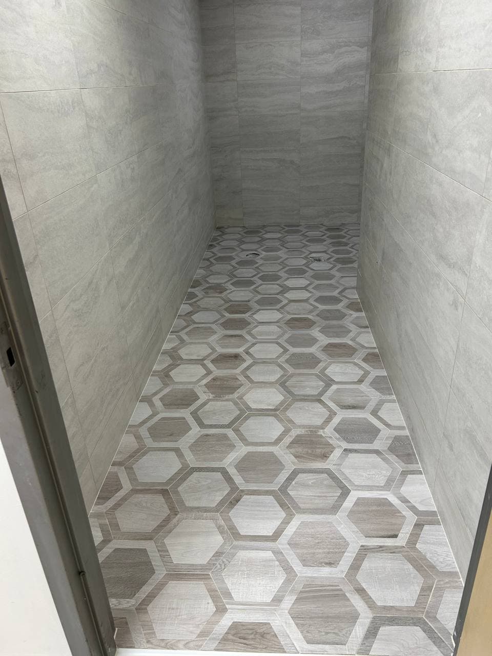 White and gray hexagon mosaic floor tile installed in a narrow interior space