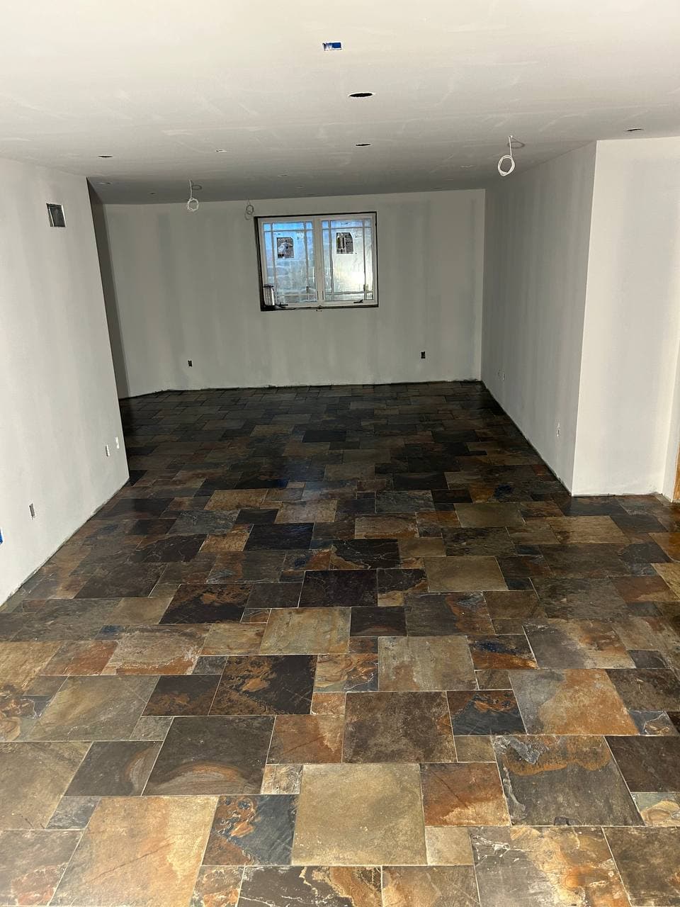 Multicolor slate-look square tile installed across a finished basement floor