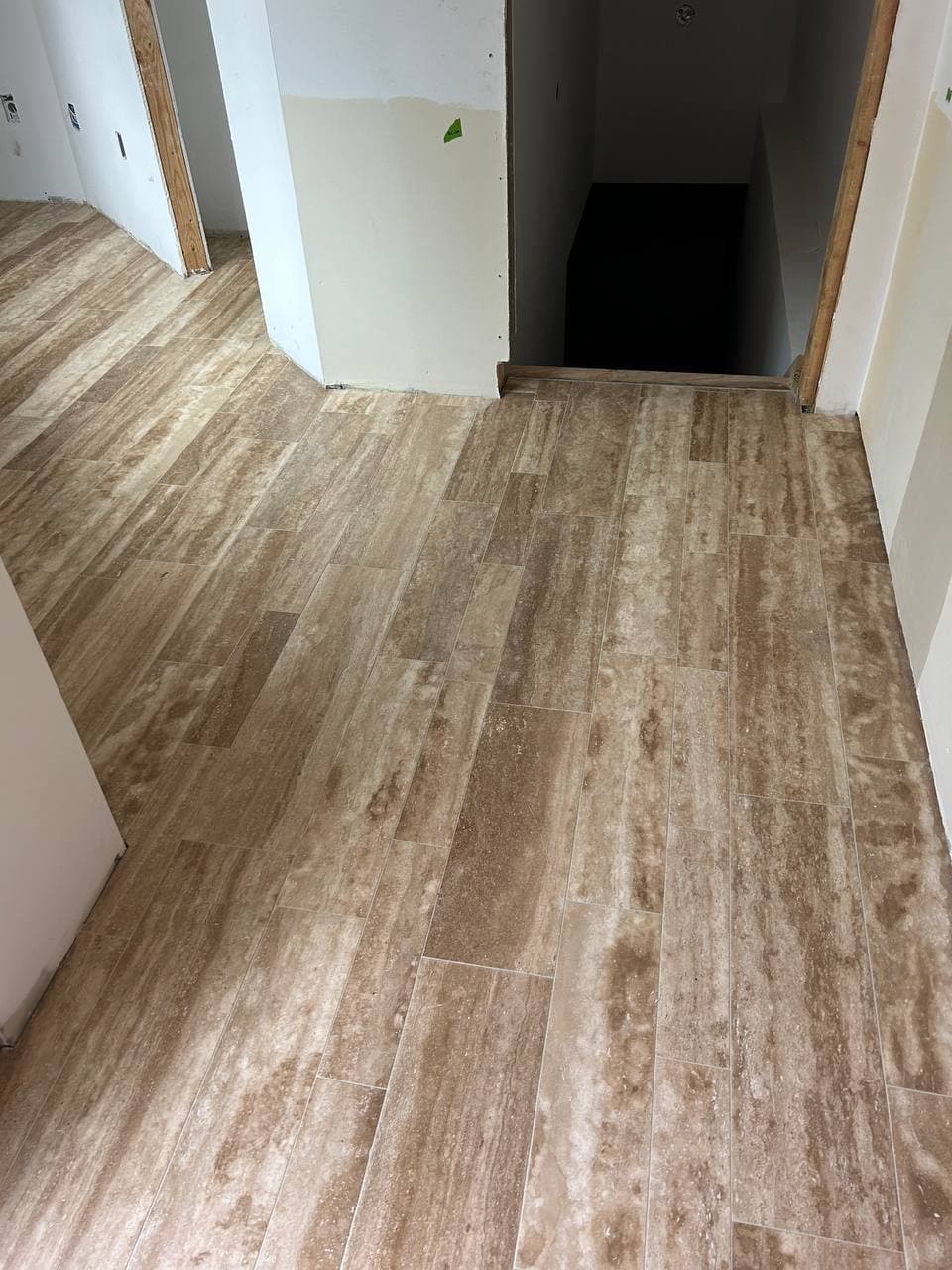 Wood-look plank tile extending through a narrow interior hallway and doorway
