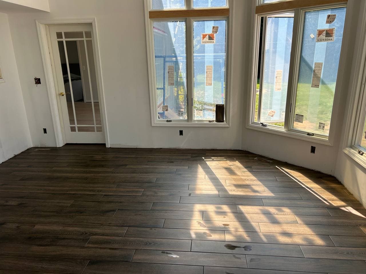 Dark wood-look plank tile installed in a sunroom with tall bay windows